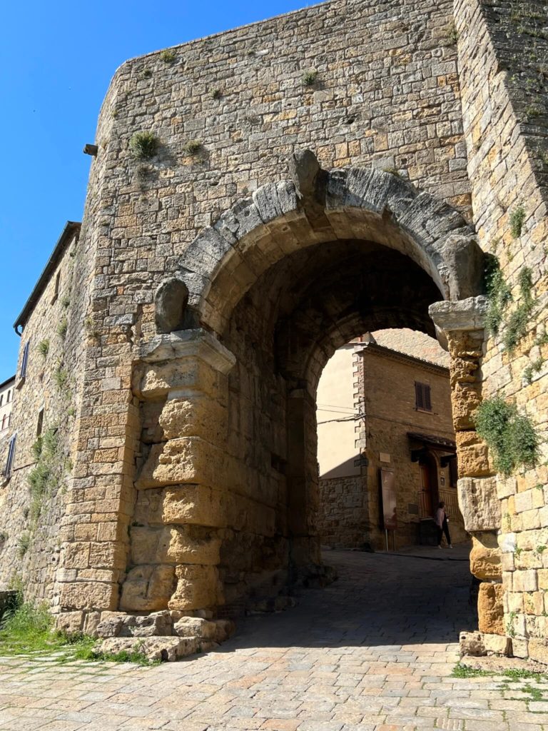 the etruscan arch in volterra, italy with three eroded sculpted heads on it