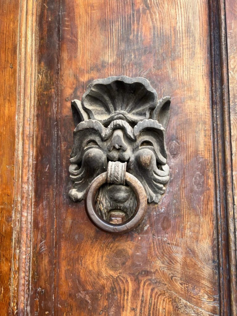 a knocker that looks like a gremlin in volterra, italy