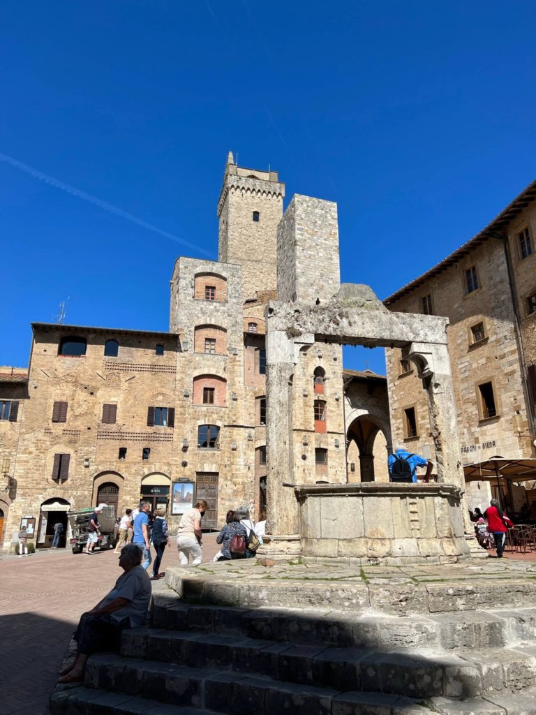 plaza in san gimignano dominated by a medieval well