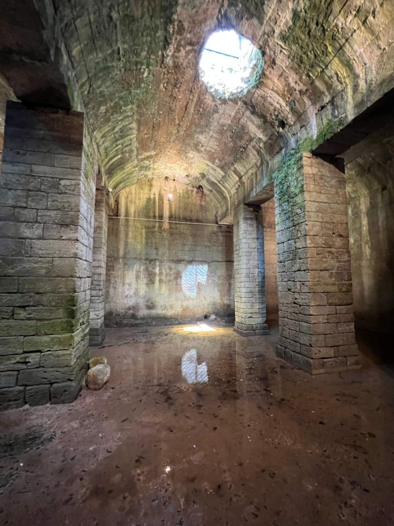 empty roman cistern with a bit of water on the ground