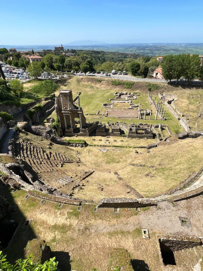 ruins of a roman theater with scant ruins of a bath behind it