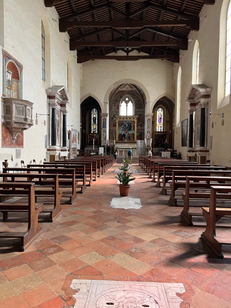 interior of a small church with frescos lined along the walls