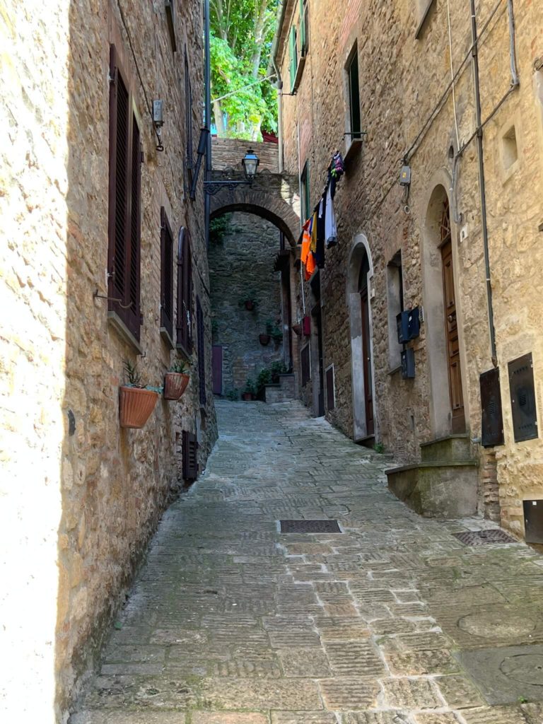 an alleyway with an arch at the end in volterra, taly