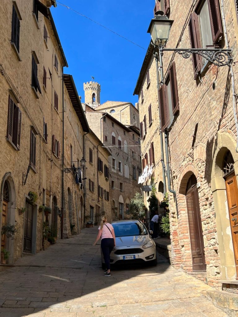 michelle walking up a winding road in volterra, italy