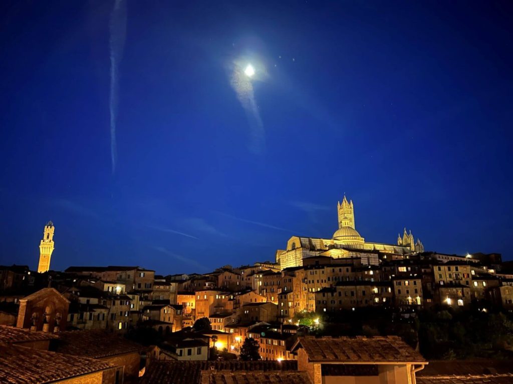 the moon rising over siena italy's skyline
